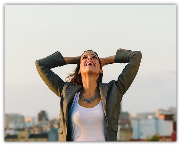Successful young businesswoman after business or job achievement towards city background. Professional joyful woman outside.